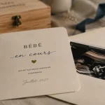 Carte annonce grossesse sur table en lin, échographie visible.
